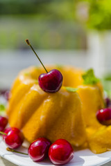 Delicious cake with fresh and ripe cherries on a table in the garden.
