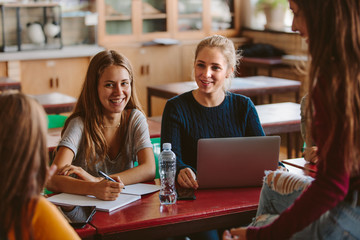 Happy students discussing studies in classroom