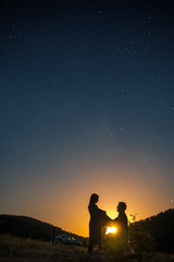 Silhouette of young couple under stars. The concept on the theme of love. romantic evening together, sunset, vertical photo, makes an offer to marry