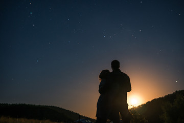 Silhouette of young couple under stars. The concept on the theme of love. romantic evening together, sunset