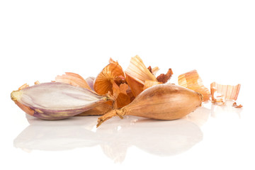 One shallot with sliced half in front of golden husk stack isolated on white background.