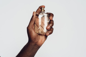 Hand of Afro American man holding perfume.