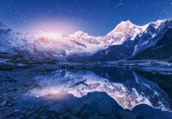 Night scene with himalayan mountains and mountain lake at starry night in Nepal. Landscape with high rocks with snowy peak and sky with stars and moon reflected in water. Moonrise Beautiful Manaslu