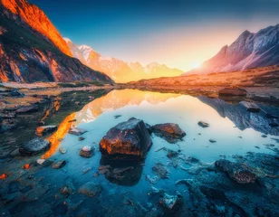 Fototapete Himalaya Wunderschöne Landschaft mit hohen Bergen mit beleuchteten Gipfeln, Steinen im Bergsee, Spiegelung, blauem Himmel und gelbem Sonnenlicht bei Sonnenaufgang. Nepal. Erstaunliche Szene mit Himalaya-Bergen. Himalaya