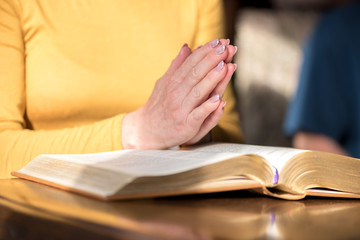 Woman praying with her hands over the bible