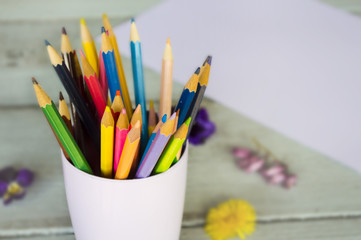 colored pencils in a glass on a wooden background