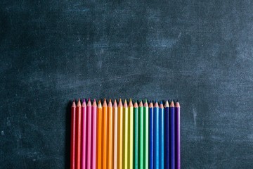 Sharpened pencils laid out by the color of the rainbow lie on the school Board