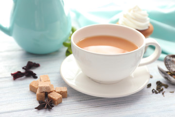Cup of aromatic tea with milk on table