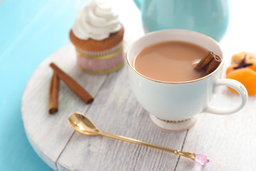 Cup of aromatic tea with milk on wooden board