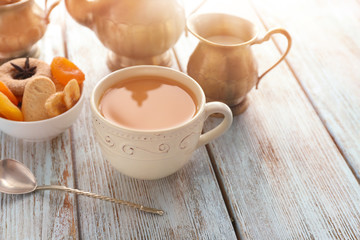 Cup of aromatic tea with milk on wooden table