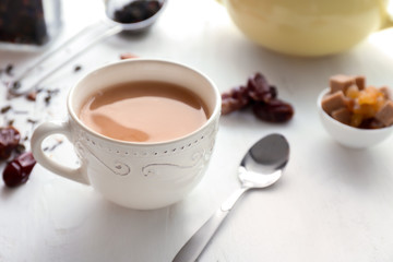 Cup of aromatic tea with milk on wooden table