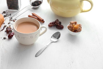 Cup of aromatic tea with milk on wooden table