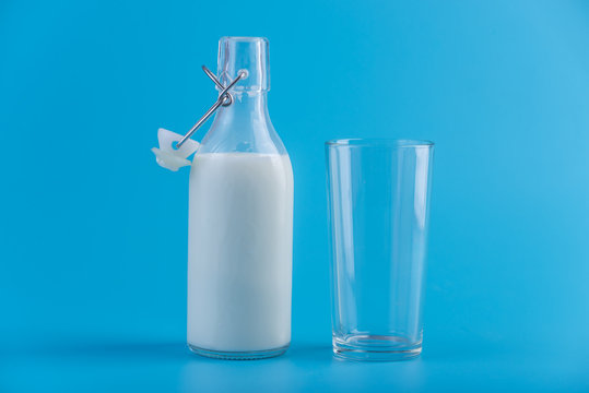 Glass bottle of fresh milk and glass on blue background. Colorful minimalism. Concept of healthy dairy products