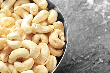 Metal bowl with fresh cashew nuts on table, closeup