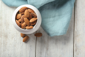 Bowl with fresh almonds on white wooden table