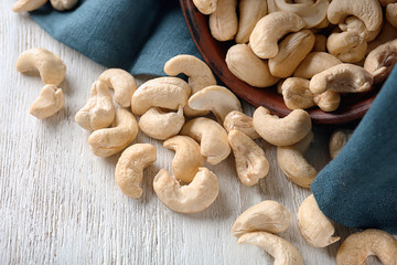 Scattered cashew nuts on white wooden table, closeup