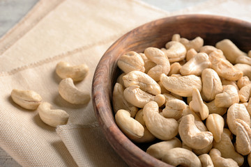 Bowl with fresh cashew nuts on table, closeup