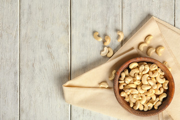 Fototapeta na wymiar Bowl with fresh cashew nuts on white wooden table