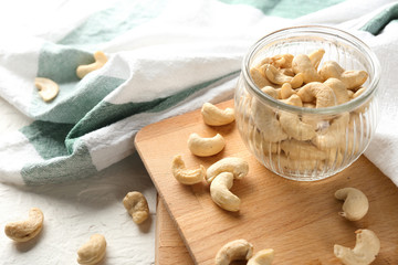 Glass jar with fresh cashew nuts on table