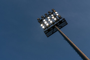Flutlichtmast mit einigen eingeschalteten Lampen vor dunkelblauem Himmel © kraichgaufoto