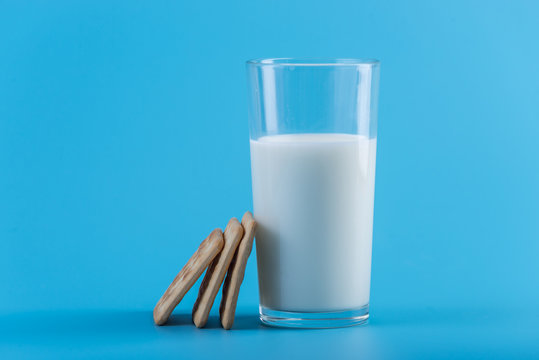 Glass of fresh milk and cookies on a blue background. Concept of healthy dairy products with calcium