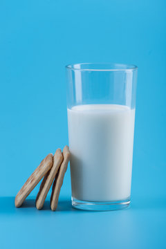 Glass of fresh milk and cookies on a blue background. Concept of healthy dairy products with calcium