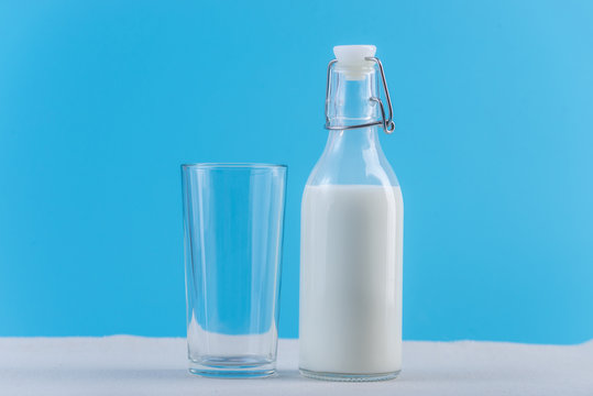 Bottle of fresh milk and glass on blue background. Colorful minimalism. Concept of healthy dairy products with calcium