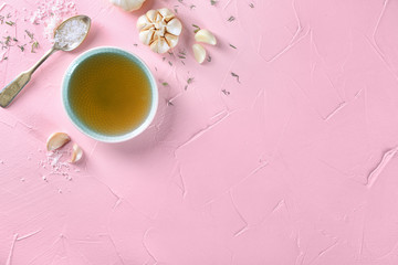 Bowl with olive oil, salt and garlic on color background, top view