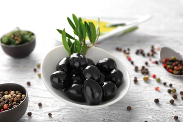 Bowl with black olives covered with oil and spices on table