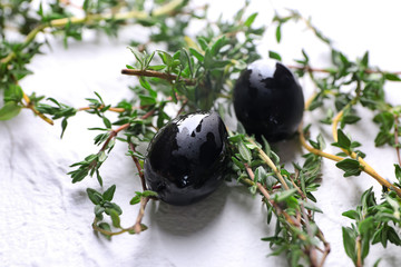 Black olives covered with oil and thyme on table