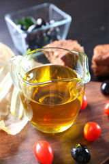 Jug of oil, black olives and cherry tomatoes on table