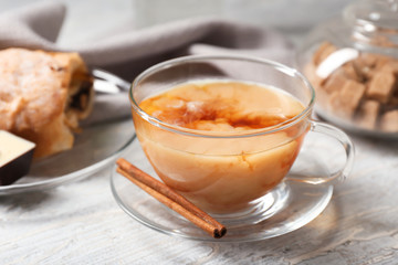 Cup of hot masala tea with cinnamon sticks on wooden table