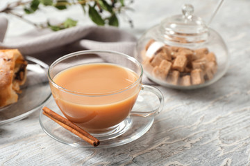 Cup of hot masala tea with cinnamon sticks on textured table