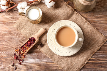 Composition with cup of hot masala tea on wooden table