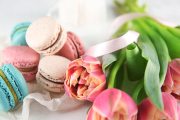 Tasty macarons and tulips on table
