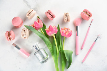Flat lay composition with tasty macarons, tulips and beauty accessories on light background