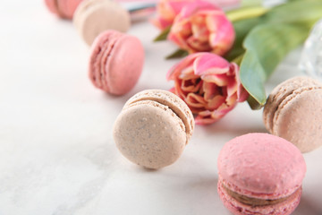 Tasty macarons and tulips on light background