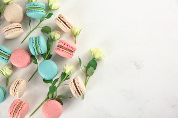 Flat lay composition with tasty macarons and roses on light background