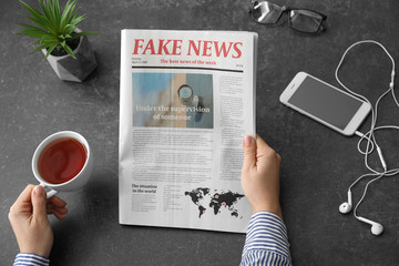Woman reading morning newspaper at dark table