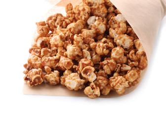 Delicious popcorn with caramel wrapped in paper on white background