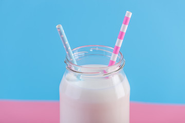 Bottle of fresh milk with two straws on pastel background. Colorful minimalism. Healthy dairy products with calcium