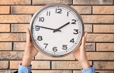 Man holding clock on brick background. Time management concept