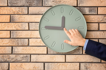 Man pointing on clock against wall background. Time management concept