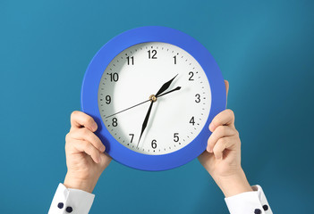 Man holding clock on color background. Time management concept