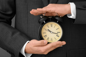 Man holding alarm clock, closeup. Time management concept