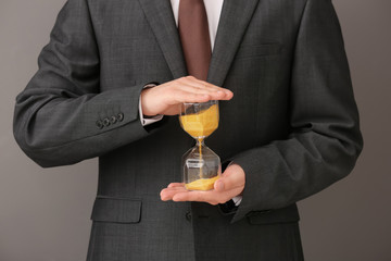 Man holding hourglass on gray background. Time management concept