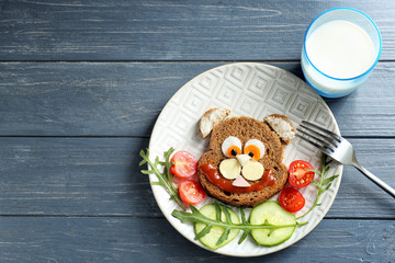 Plate with creative toast for children on wooden background, top view