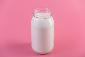 Glass bottle with fresh milk on pink background. Colorful minimalism. Healthy dairy products with calcium