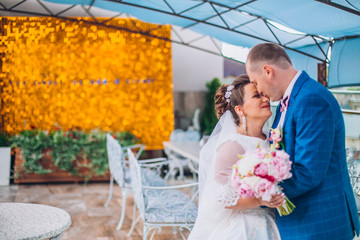 A cute groom kisses a beautiful bride's  on the roof. Newlyweds on a sunny day against the backdrop...