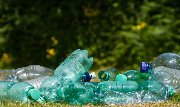 Close up on Empty Plastic bottles in a green nature park, littering of the environment background.
